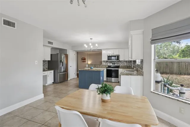 a kitchen with stainless steel appliances kitchen island granite countertop a refrigerator a stove top oven a sink with island and chairs