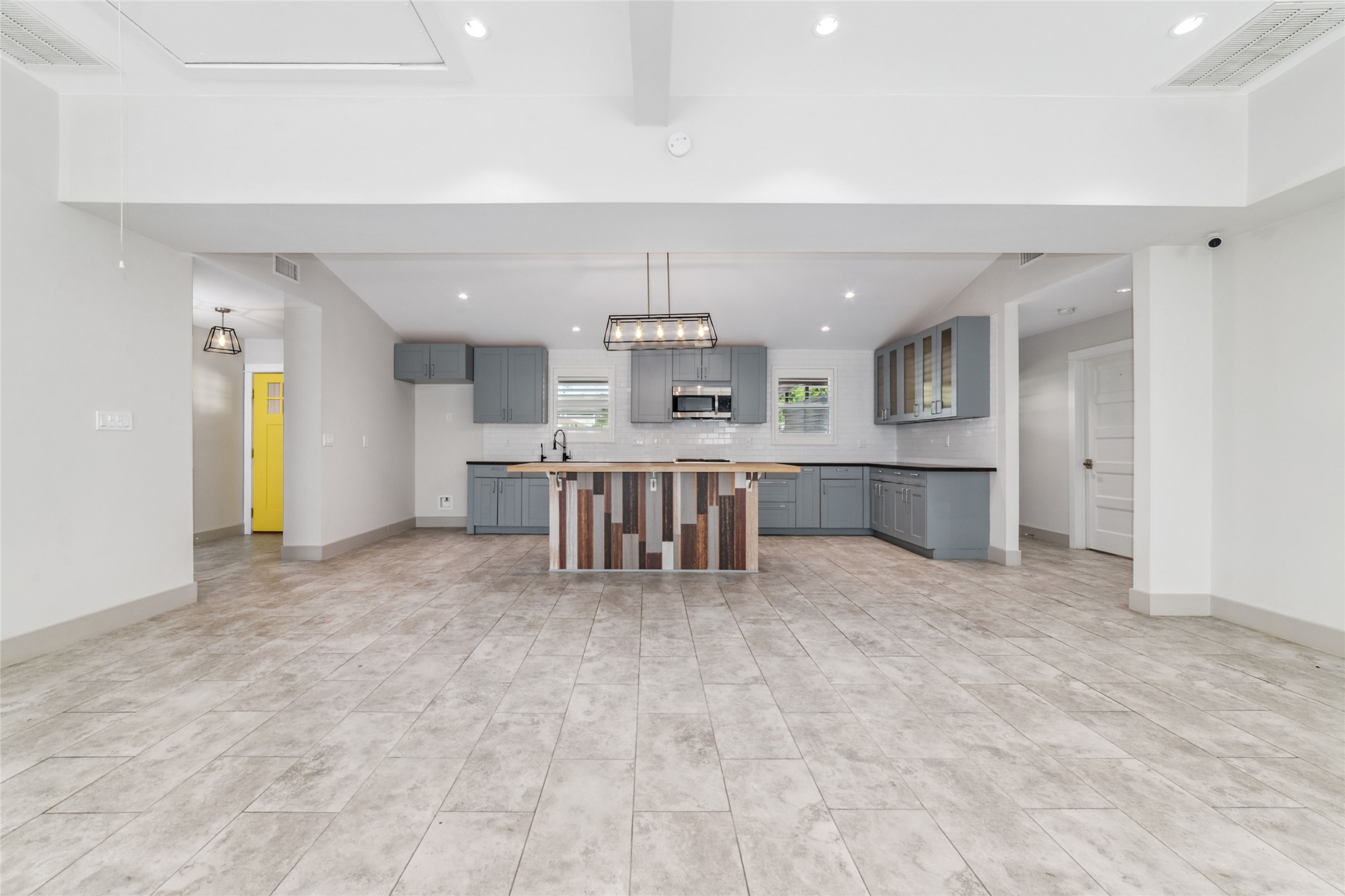 9400 Spring Branch Drive Houston, TX 77080 - Photo 13 of 45 Spacious open-concept kitchen with modern gray cabinetry, a stylish island, and sleek tile flooring, perfect for entertaining.