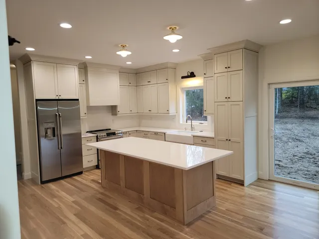 a large kitchen with stainless steel appliances kitchen island granite countertop a refrigerator and a sink