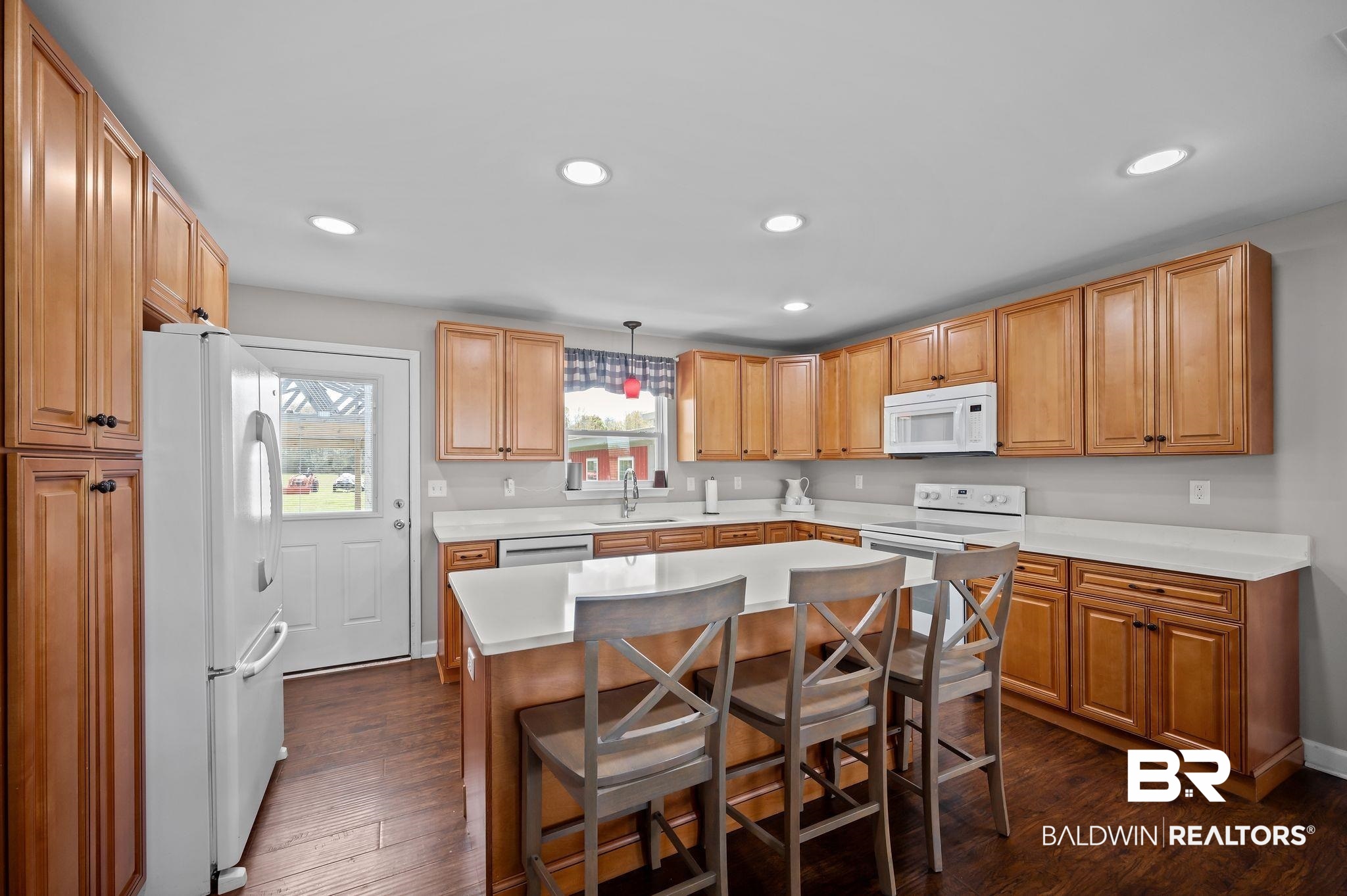 24924 Brewer Road Robertsdale, AL 36567 - Photo 9 of 33 Kitchen featuring light countertops, a breakfast bar area, a center island, dark wood-style floors, and white appliances