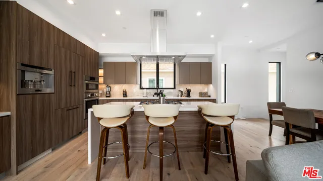 a kitchen with a dining table chairs and wooden floor