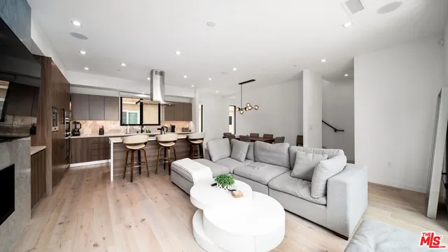 a living room with furniture kitchen view and a wooden floor