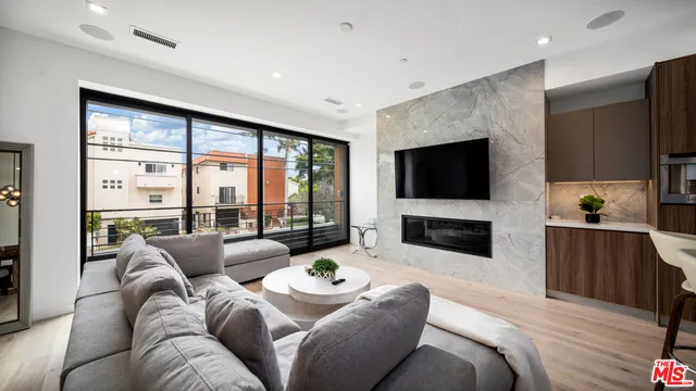 a living room with furniture a flat screen tv and a floor to ceiling window