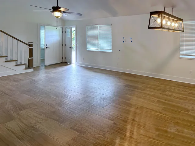 an empty room with wooden floor fan and windows