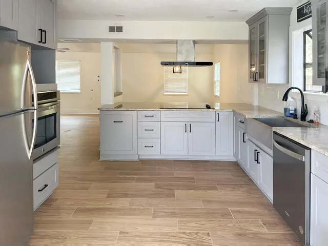 a large kitchen with stainless steel appliances granite countertop a stove and a sink