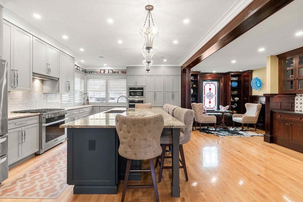 79 Wedge Street Lowell, MA 01851 - Photo 15 of 42 a kitchen with stainless steel appliances granite countertop a stove top oven a sink dishwasher a dining table and chairs with wooden floor
