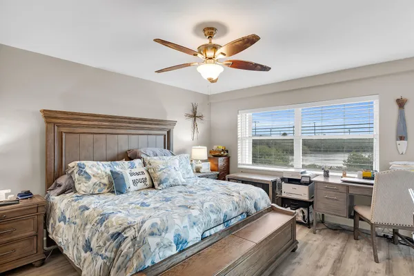 a bedroom with a bed and a large window with wooden floor