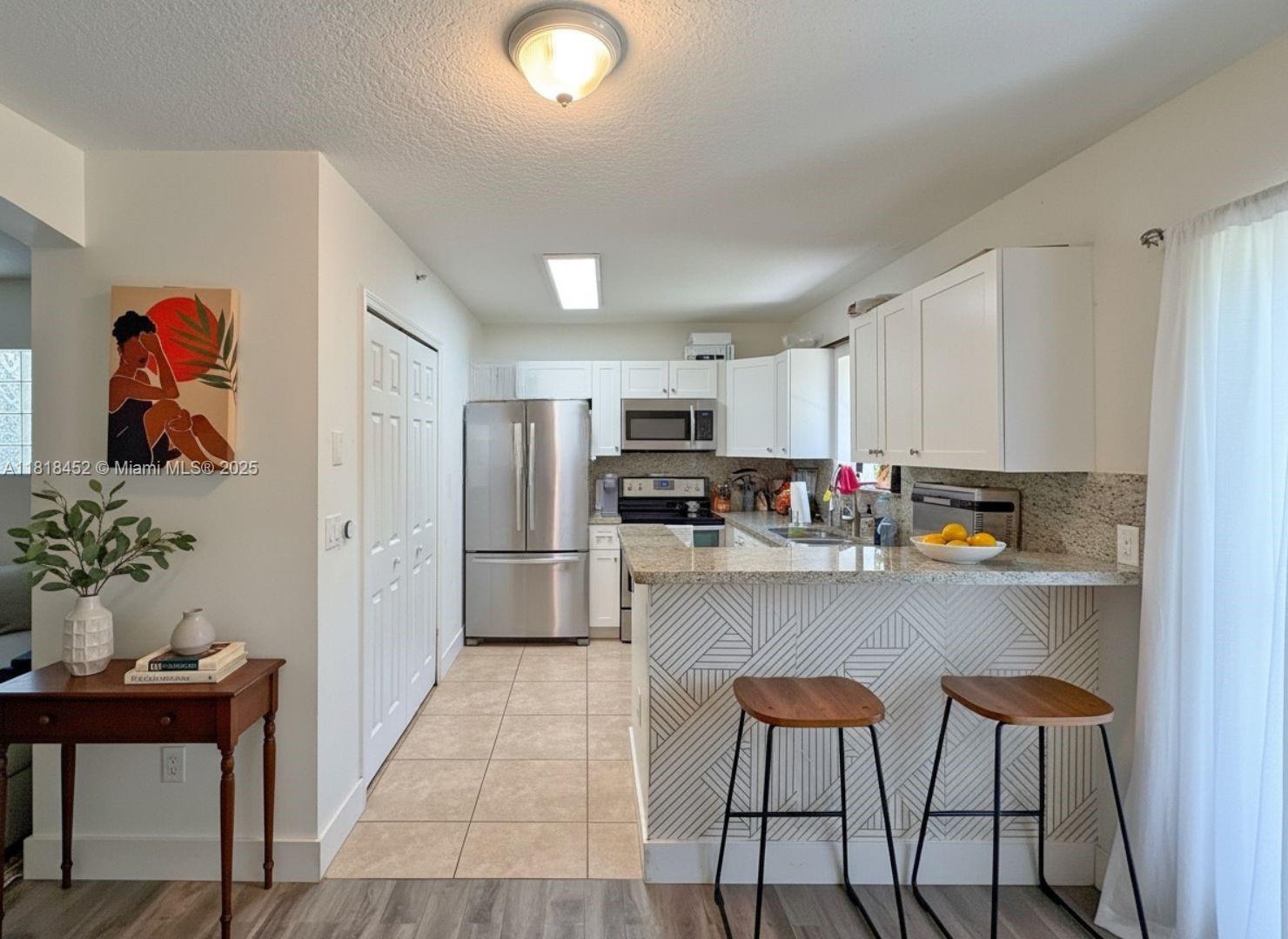 22901 Southwest 88th Place, Unit 101 Cutler Bay, FL 33190 - Photo 3 of 16 a kitchen with granite countertop a refrigerator and a stove top oven