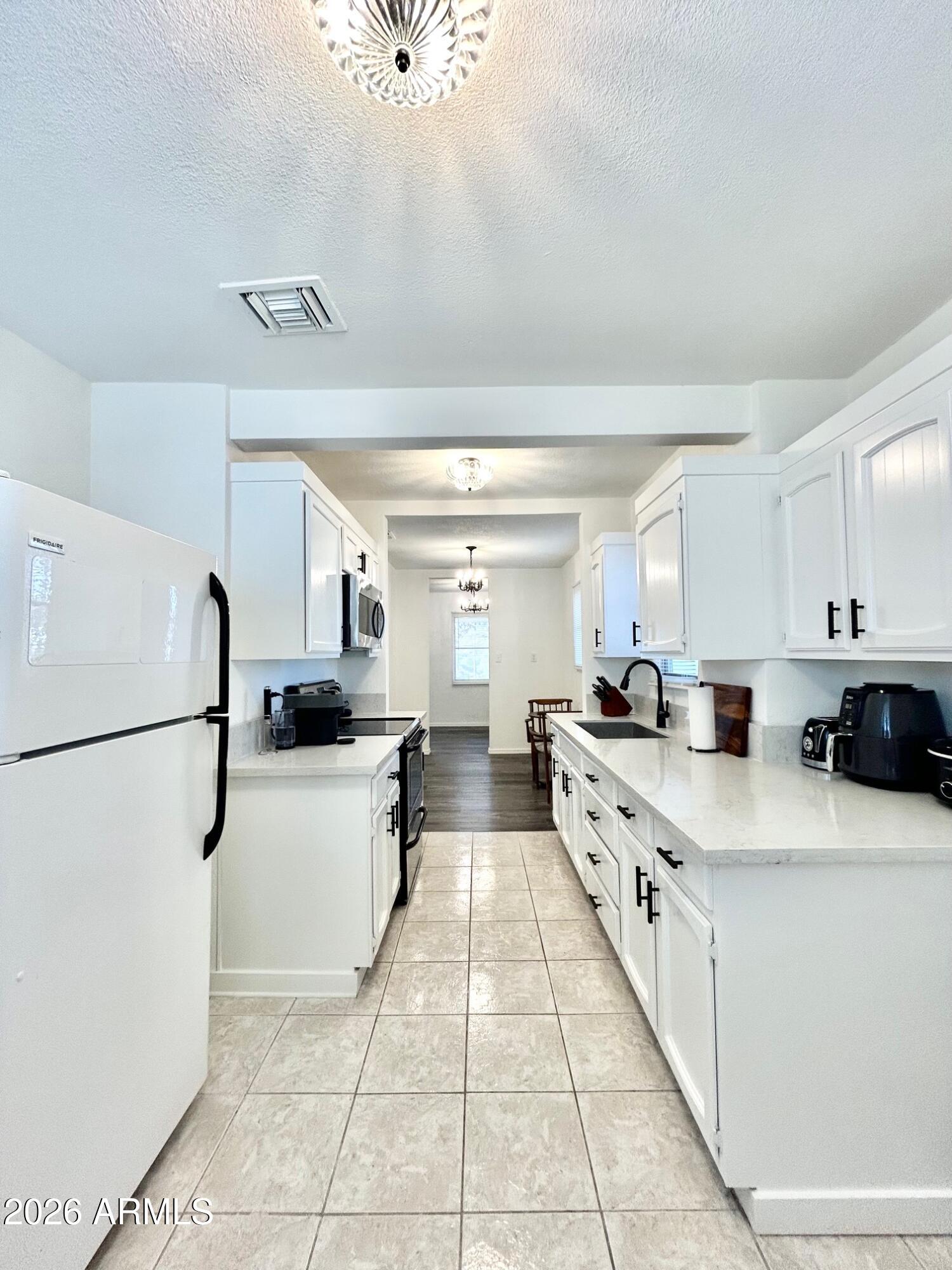 702 Paxton Avenue Miami, AZ 85539 - Photo 4 of 15 a large white kitchen with a stove a refrigerator a sink and dishwasher