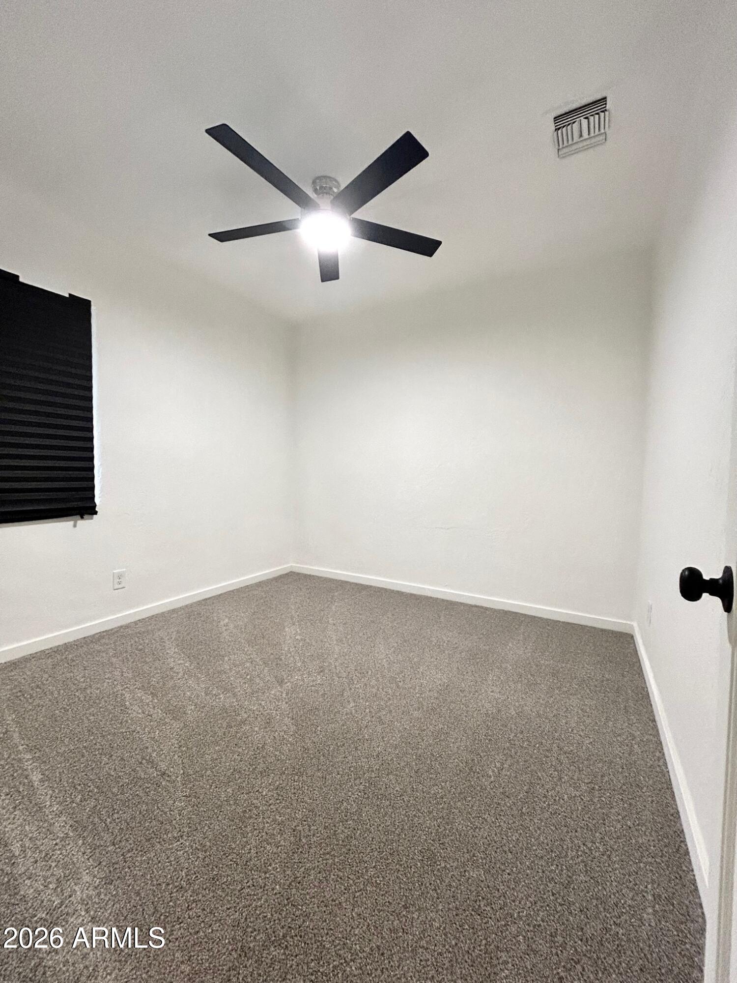 702 Paxton Avenue Miami, AZ 85539 - Photo 9 of 15 an empty room with a ceiling fan and windows