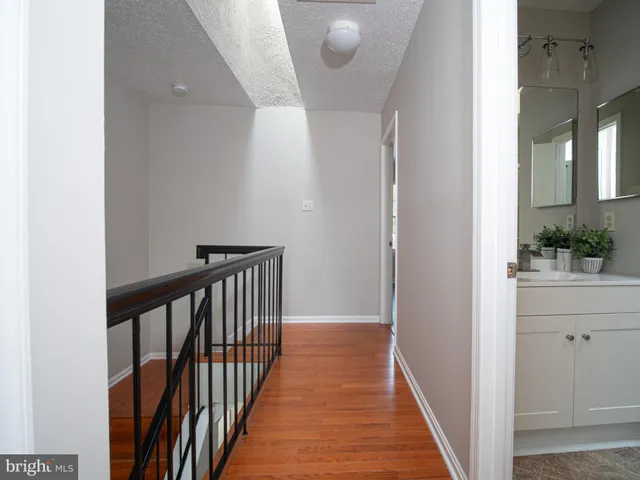 a view of a hallway with wooden floor and a bathroom