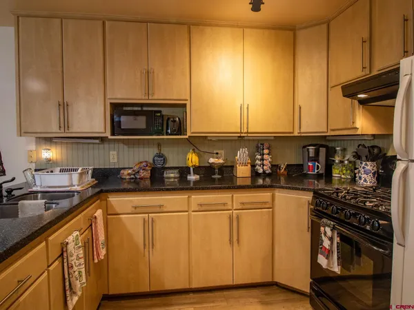 a kitchen with stainless steel appliances granite countertop a refrigerator a stove top oven a sink and dishwasher