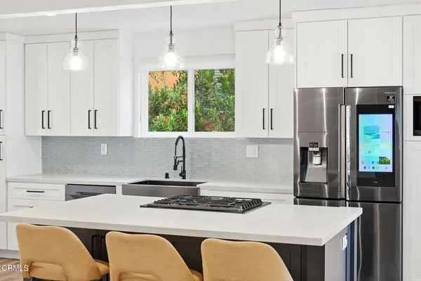 a kitchen with stainless steel appliances granite countertop a table chairs and a refrigerator