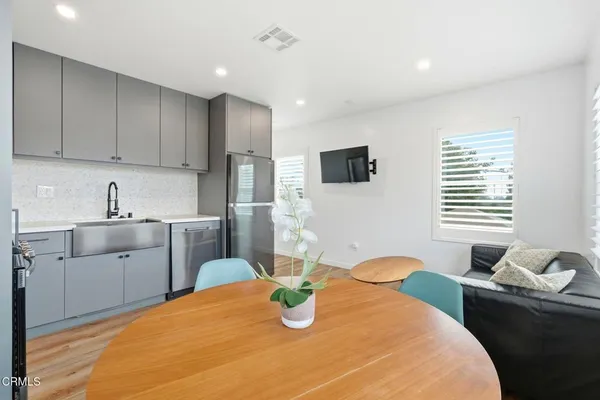 a kitchen with stainless steel appliances granite countertop a sink dishwasher a stove and a refrigerator with wooden floor