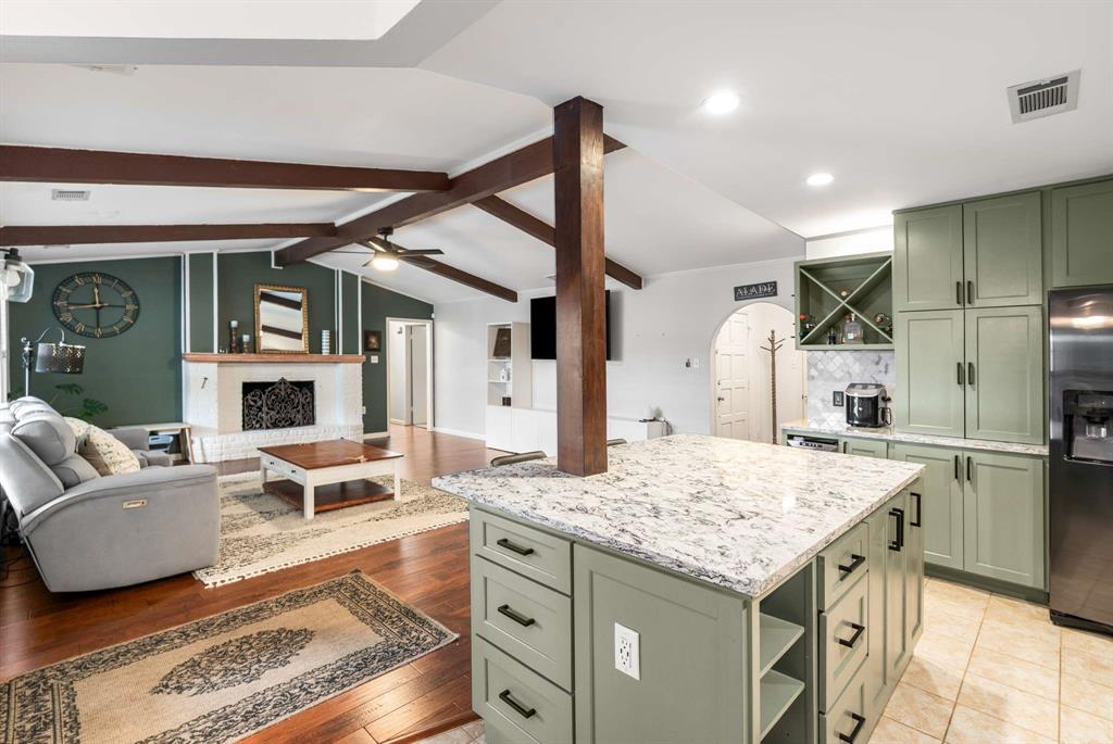 Kitchen featuring green cabinetry, stainless steel refrigerator with ice dispenser, and open shelves