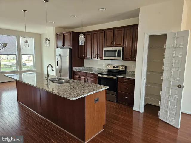 a kitchen with stainless steel appliances granite countertop a sink stove microwave and refrigerator
