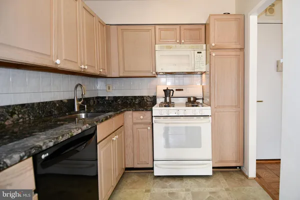 a kitchen with granite countertop white cabinets and white appliances