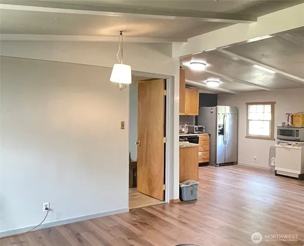 a view of a kitchen with a refrigerator a stove top oven and wooden floor
