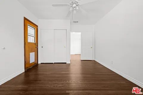 an empty room with wooden floor chandelier fan and windows