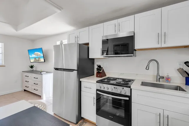 a kitchen with stainless steel appliances white cabinets white stove a sink and a refrigerator