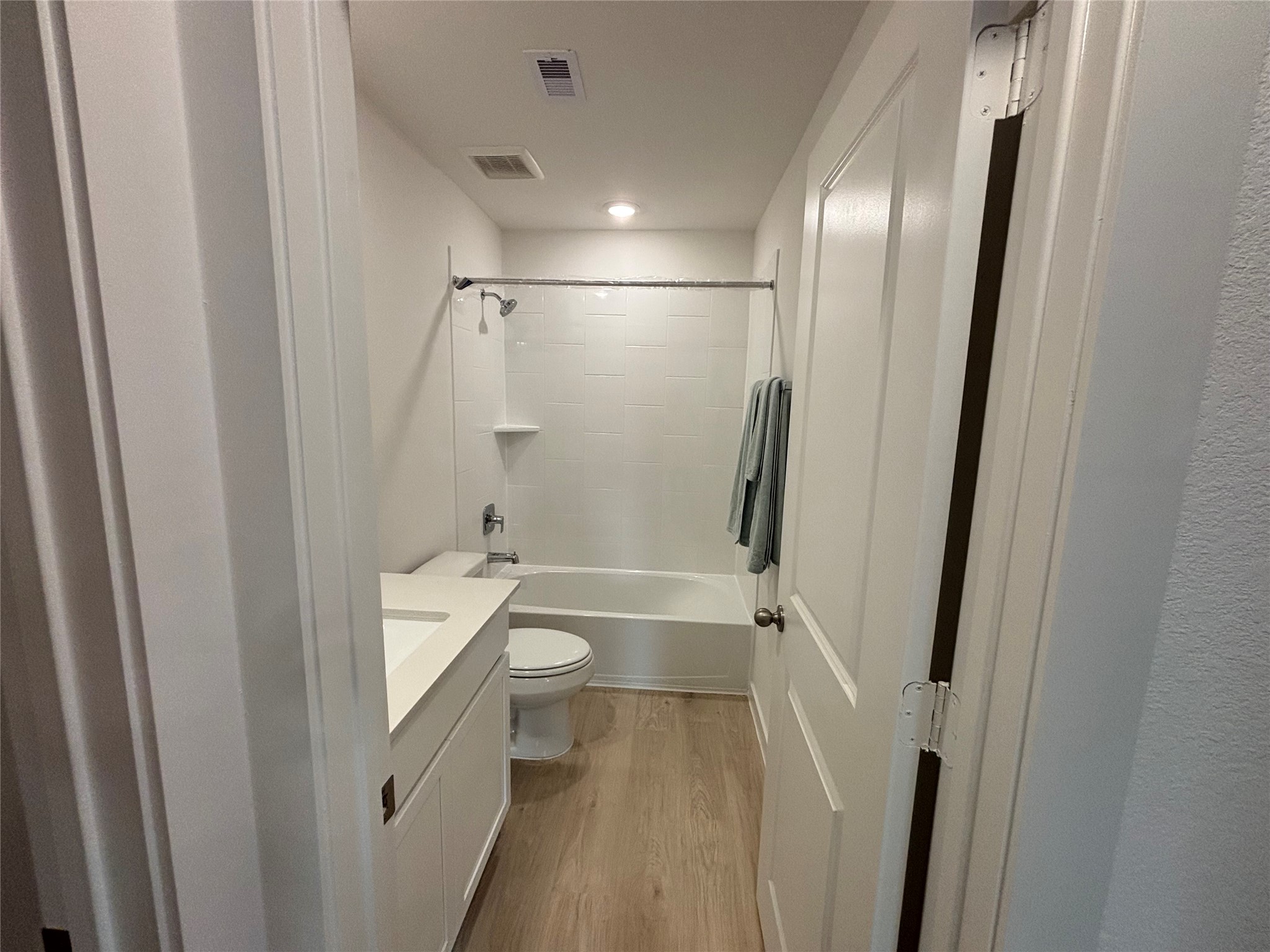 4315 Windsor Forest Fulshear, TX 77494 - Photo 34 of 50 This is another secondary bathroom a modern, compact bathroom featuring a bathtub with a shower, a white vanity with storage, and wood-look flooring. The clean, neutral design offers a fresh and inviting feel.