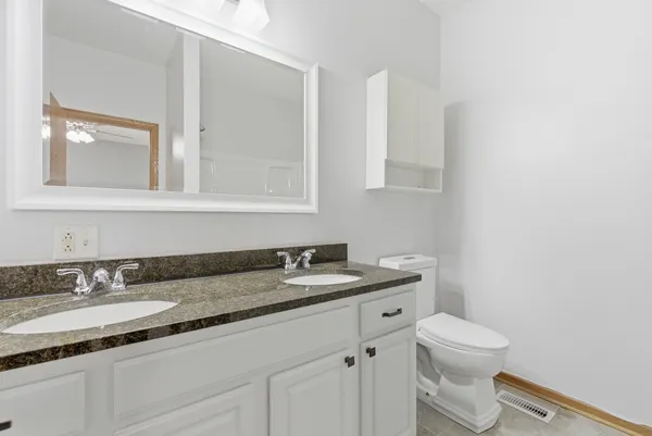 a bathroom with a granite countertop toilet sink and mirror