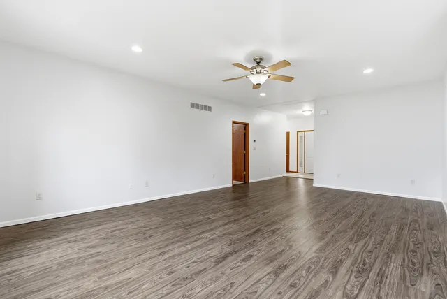 an empty room with wooden floor and a ceiling fan