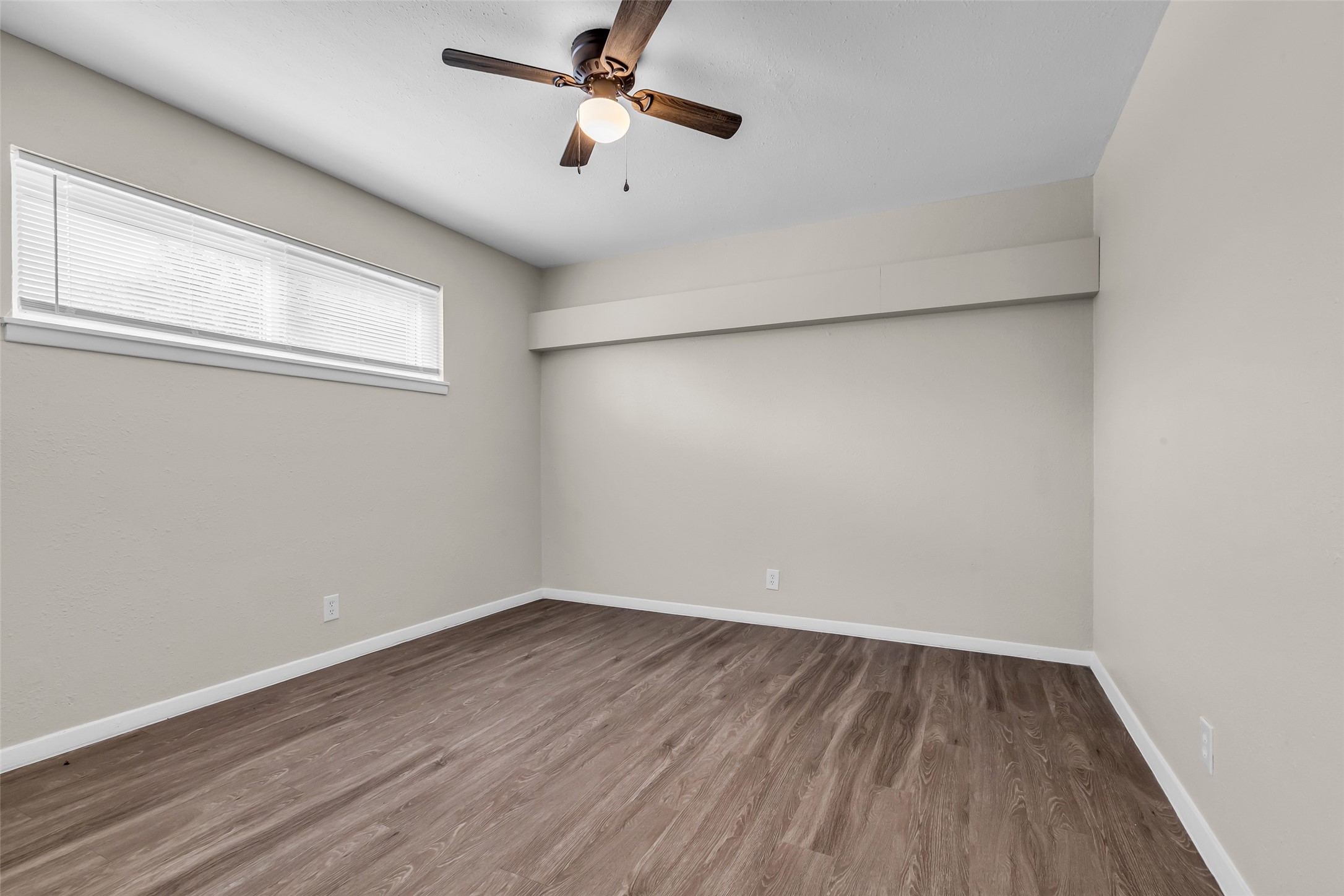 4706 Yellowstone Boulevard, Unit 5 Houston, TX 77021 - Photo 4 of 14 This room features a ceiling fan, neutral walls, and wood-look flooring. A horizontal window provides natural light, creating a bright and airy space. Perfect for a bedroom or office.