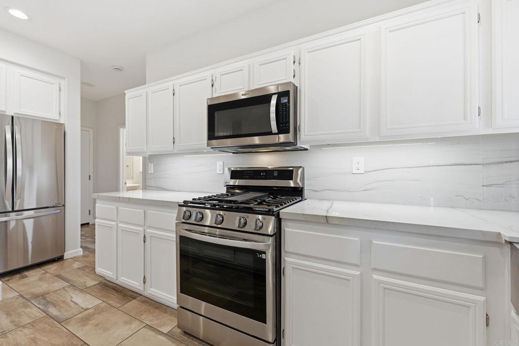 5051 Lake Circle Road Fallbrook, CA 92028 - Photo 12 of 57 a kitchen with white cabinets and stainless steel appliances
