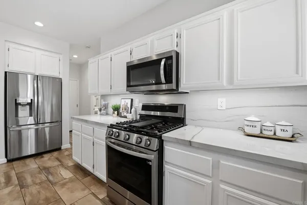 a kitchen with stainless steel appliances granite countertop white cabinets a stove a sink and a white wooden cabinets