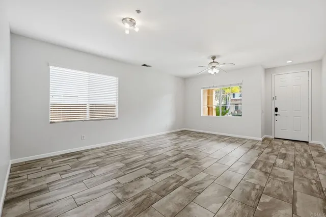 a view of an empty room with a fireplace and chandelier fan