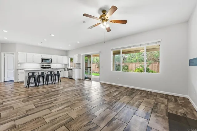 an empty room with wooden floor cabinet and windows