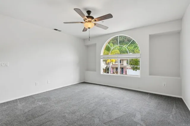 an empty room with windows and fan