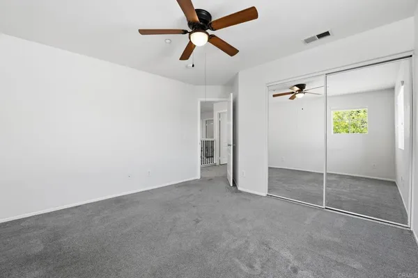 an empty room with a window and a fan