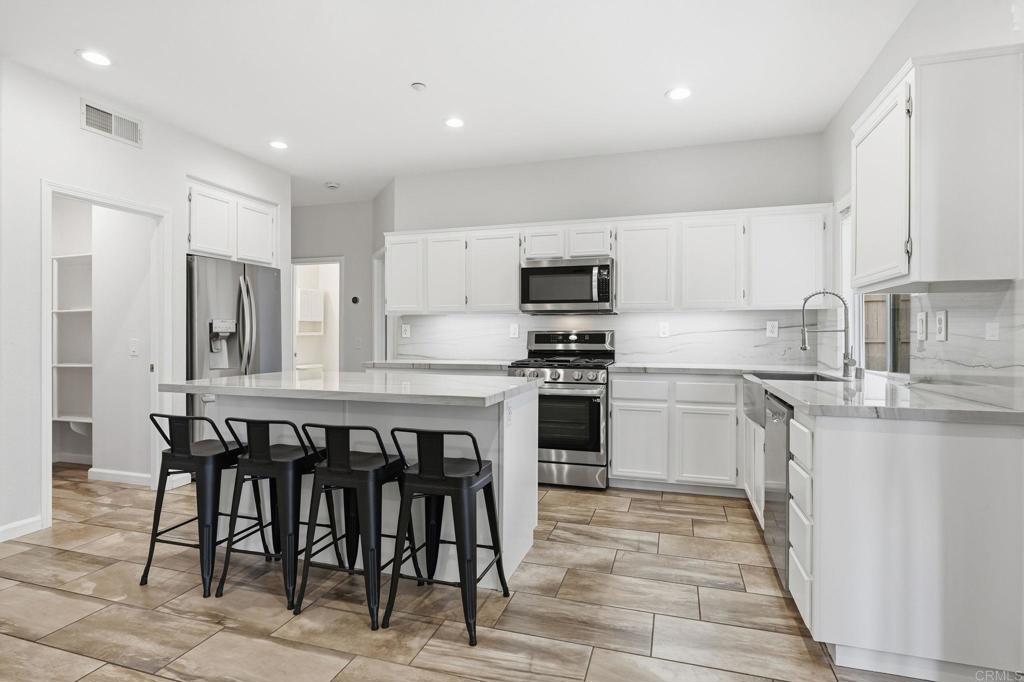 5051 Lake Circle Road Fallbrook, CA 92028 - Photo 6 of 57 a kitchen with stainless steel appliances a table chairs sink and cabinets