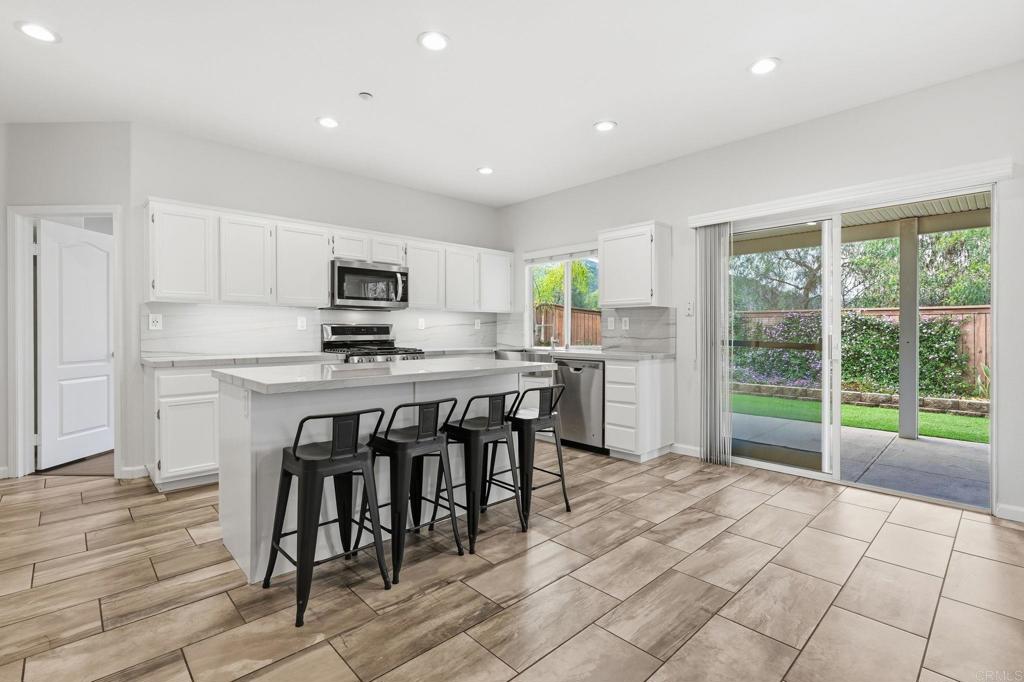 5051 Lake Circle Road Fallbrook, CA 92028 - Photo 8 of 57 a kitchen with kitchen island granite countertop a stove a sink a microwave a island with a dining table and chairs