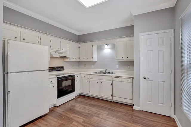 a kitchen with cabinets appliances wooden floor and a window