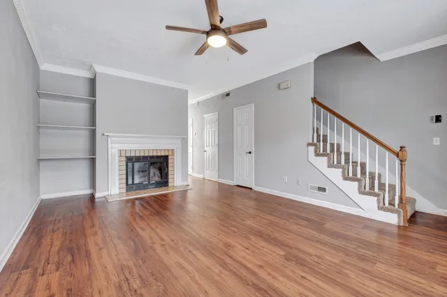 a view of an empty room with wooden floor fireplace and a window