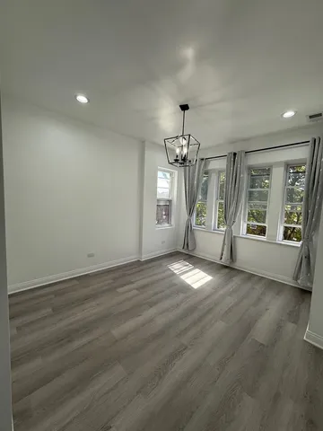 an empty room with wooden floor and chandelier