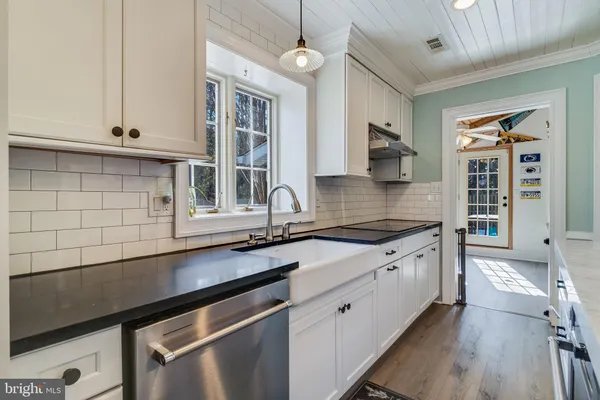 a kitchen with granite countertop stainless steel appliances a sink stove and cabinets