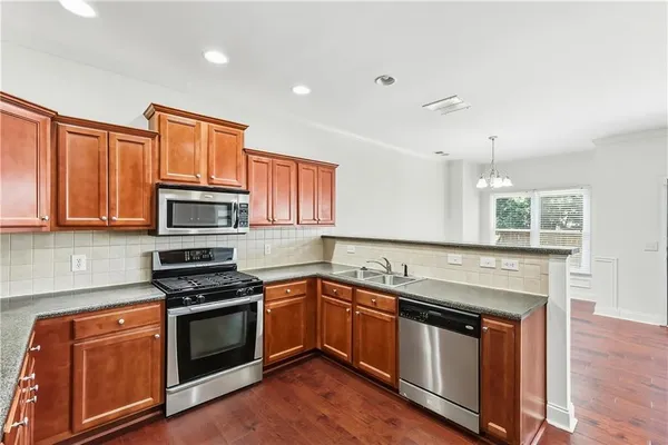 a kitchen with stainless steel appliances granite countertop wooden floor sink stove and microwave