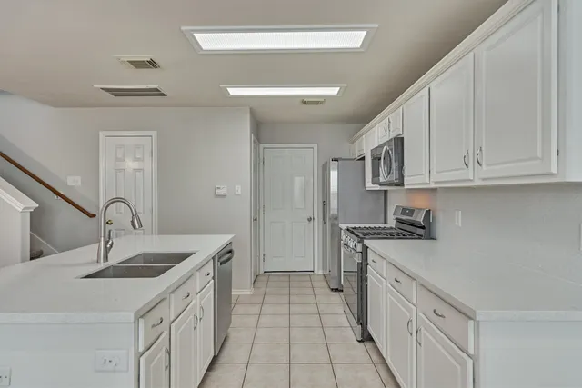a kitchen with a sink a stove cabinets and a glass door