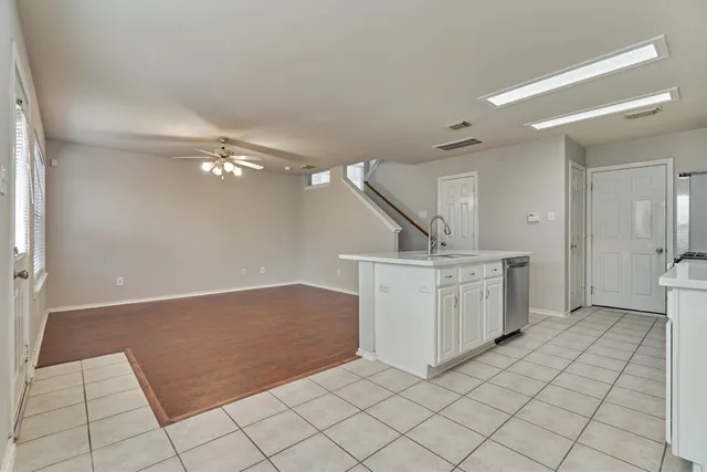 an empty room with wooden floor chandelier fan and windows