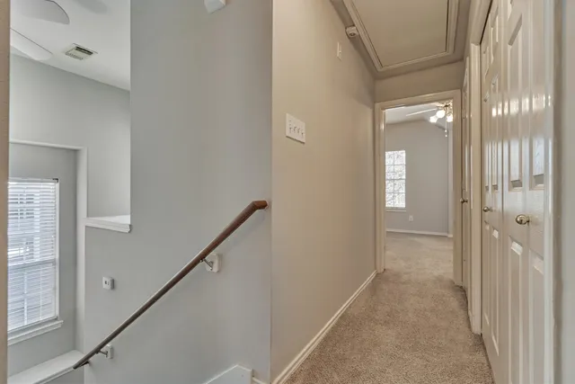an empty room with windows and chandelier fan