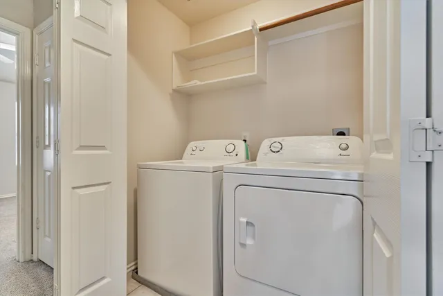 an empty room with a chandelier fan and windows