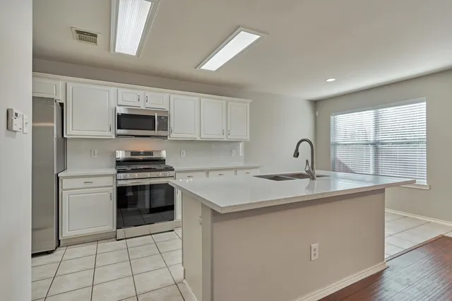 a kitchen with white cabinets a sink and appliances