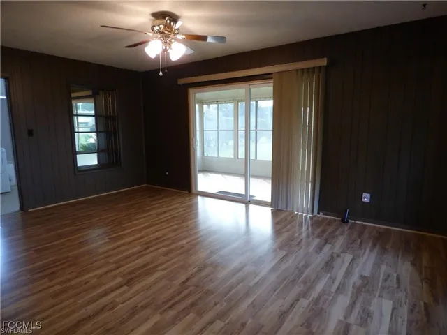a view of empty room with wooden floor and fan