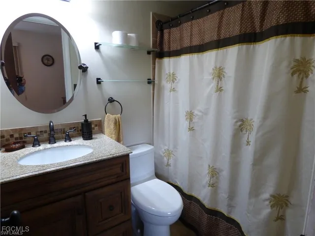 a bathroom with a granite countertop sink toilet and a mirror