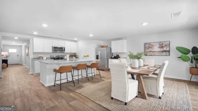 a room with stainless steel appliances kitchen island granite countertop lots of white furniture a dining table and chairs