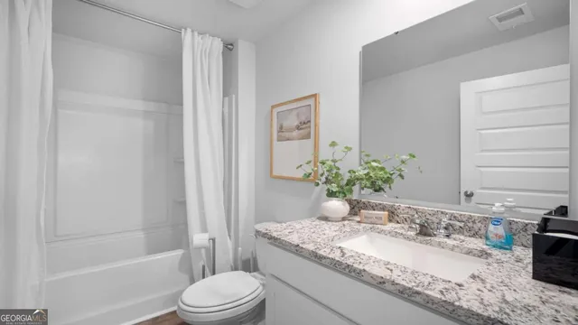 a bathroom with a granite countertop sink toilet and shower